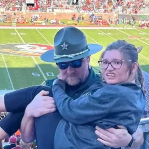 Image of Florida deputy carrying girl struggling to walk up stadium stairs at football game goes viral