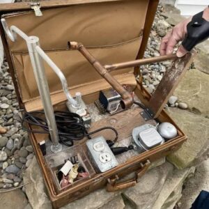 Found a locked briefcase under an old wood shed floor: Inside are power supplies / plugs, a 9V battery, alarm, removable piping and a removable bracket Found a locked briefcase under an old wood shed floor: Inside are power supplies / plugs, a 9V battery, alarm, removable piping and a removable bracket